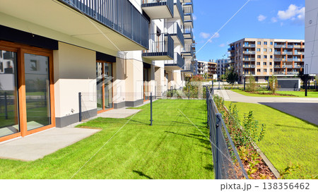 The garden of a modern residential building with a green lawn and a place to relax. Home garden. The garden of a modern residential building with a green lawn and a place to relax. Home garden. 138356462