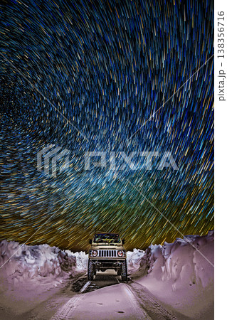 雪原の道と満天の星、静寂の中の車のシルエット 138356716