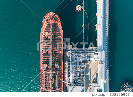 Aerial top down view of a large oil tanker docked at a pier in the port in process of loading. 138356998