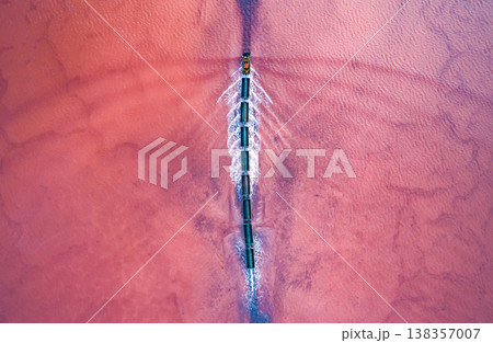 Aerial view of an old train rides on the railway laid in the water through the salt lake. Salt mining in Lake Burlin. Altai. Bursol. 138357007