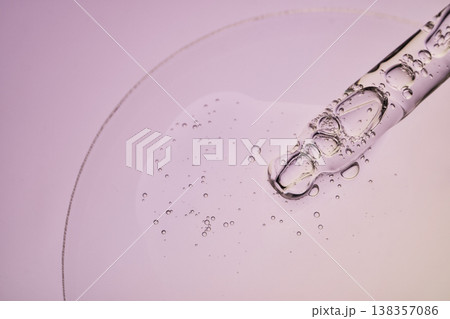 Clear liquid serum dropping from glass pipette creating small bubbles Clear liquid serum dropping from glass pipette creating small bubbles 138357086