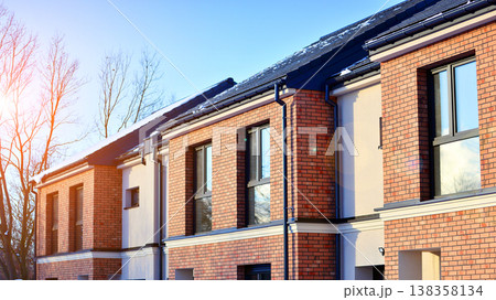 The real estate market in the suburbs. Terraced family homes in newly developed housing estate. New single family houses in a new development area. Residential homes with modern facade. The real estate market in the suburbs. Terraced family homes in newly developed housing estate. New single family houses in a new development area. Residential homes with modern facade. 138358134
