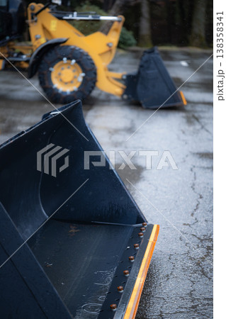 冬の作業を終えて雨に濡れる黄色い除雪車とバケット 138358341