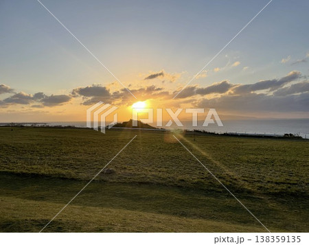 草原越しに輝く夕日と穏やかな海の眺め 138359135