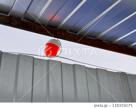 A vivid red lantern is gracefully suspended beneath a roof, casting a warm, inviting light over a cozy sheltered area A vivid red lantern is gracefully suspended beneath a roof, casting a warm, inviting light over a cozy sheltered area 138359275