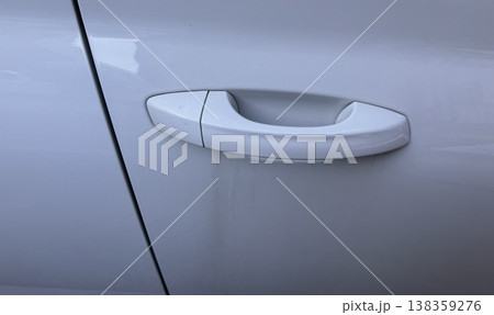 A close-up of a white door handle with a closed cap for a car lock on a clean, modern body, showing smooth lines and elegant design. Efficient transportation systems are essential for economic growth. 138359276