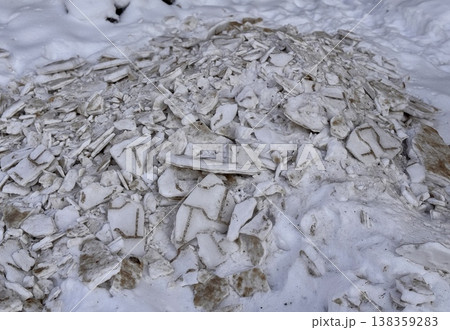 A pile of shattered ice pieces is scattered on a snowcovered ground, showcasing winters unique and beautiful textures. 138359283