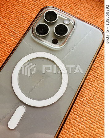 ALMATY, KAZAKHSTAN - FEBRUARY 27, 2025: Apple Iphone 15 pro max color natural lies on an orange background on a table with cameras facing up for sale in a studio room. Close-up. 138359292