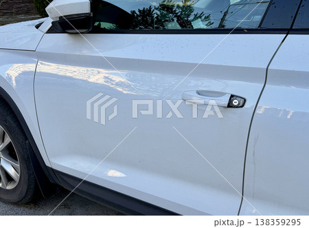 A close-up of a white door handle with a removed or stolen car lock cover on a clean, modern body, showing smooth lines and elegant design. Efficient transportation systems are essential for economic 138359295