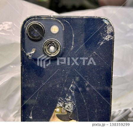 ALMATY, KAZAKHSTAN - FEBRUARY 27, 2025: The back of a broken glass gold side of a broken iPhone 13 Pro displayed on a showcase shelf in an electronics store. Close-up. 138359299