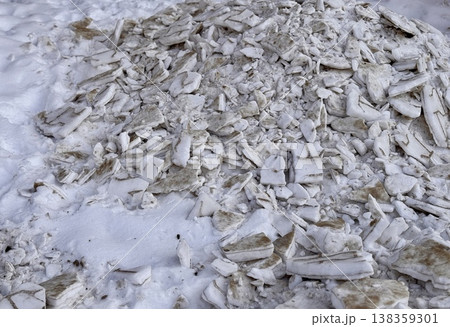 A pile of shattered ice pieces is scattered on a snowcovered ground, showcasing winters unique and beautiful textures. 138359301