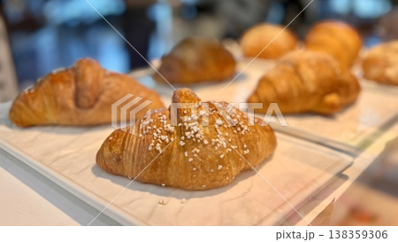 Freshly baked almond croissants with a wide assortment are elegantly laid out in a beautiful showcase for regular visitors. Close-up. Freshly baked almond croissants with a wide assortment are elegantly laid out in a beautiful showcase for regular visitors. Close-up. 138359306