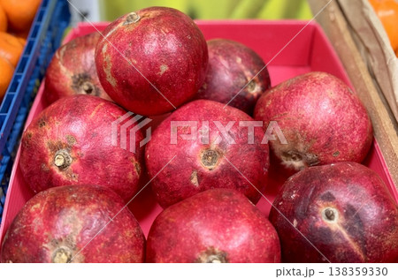 A lot of ripe red pomegranates in a basket on a market counter for sale on sale in vegetable stand display at supermarket show organic food, vegetarian food, healthy food. Close-up. A lot of ripe red pomegranates in a basket on a market counter for sale on sale in vegetable stand display at supermarket show organic food, vegetarian food, healthy food. Close-up. 138359330