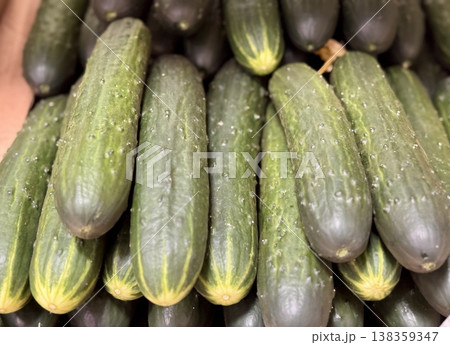 A lot of green cucumbers in a market counter for sale on sale in vegetable stand display at supermarket show organic food, vegetarian food, healthy food. Close-up. 138359347