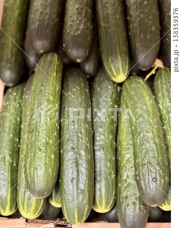 A lot of green cucumbers in a market counter for sale on sale in vegetable stand display at supermarket show organic food, vegetarian food, healthy food. Close-up. 138359376