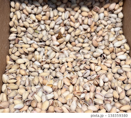 A lot of fried selected clean delicious pistachios for sale in a box at a local specialty market. Close-up. 138359380