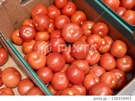 A vibrant display of ripe cherry tomatoes stacked neatly in a green basket at a bustling local market. Close-up. 138359401