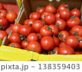 A vibrant display of ripe cherry tomatoes stacked neatly in a yellow basket at a bustling local market. Close-up. 138359403