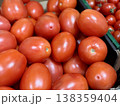 A vibrant display of ripe cherry tomatoes stacked neatly in a green basket at a bustling local market. Close-up. 138359404
