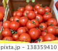 A vibrant display of ripe cherry tomatoes stacked neatly in a yellow basket at a bustling local market. Close-up. 138359410