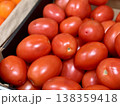 A vibrant display of ripe cherry tomatoes stacked neatly in a green basket at a bustling local market. Close-up. 138359418