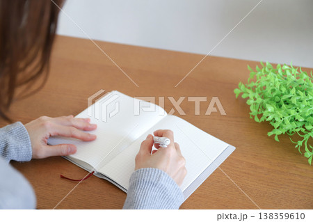 机で手帳にペンで書き込む女性 138359610