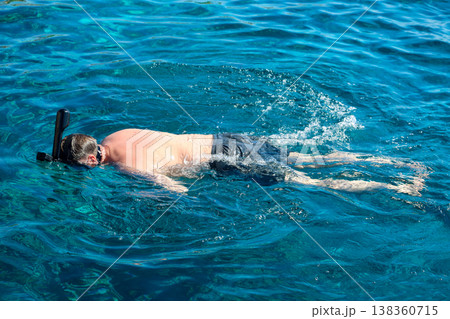 A man in a mask floats on the surface of the Red Sea and looks into the depths A man in a mask floats on the surface of the Red Sea and looks into the depths 138360715