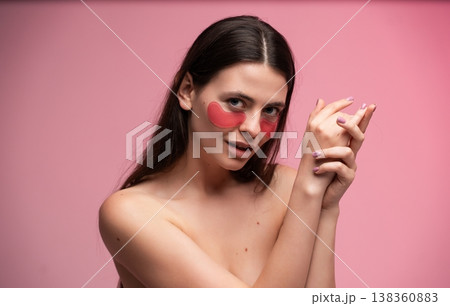 Young woman applying pink hydrating eye patches for skincare and self-care routine, enjoying pampering and beauty treatment on a vibrant pink background Young woman applying pink hydrating eye patches for skincare and self-care routine, enjoying pampering and beauty treatment on a vibrant pink background 138360883