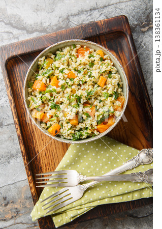 Bulgur salad with parsley and dried apricots close-up in a bowl. Vertical top view 138361134
