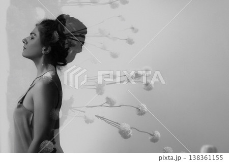 Double exposure portrait of young Caucasian woman with flowers, side view, monochrome background 138361155