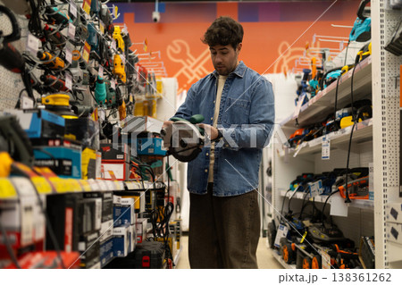 Man holding a circular saw, shopping for power tools in a retail hardware store Man holding a circular saw, shopping for power tools in a retail hardware store 138361262