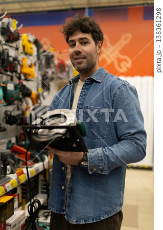 Young man shopping for electric saw in a diy home improvement retail store 138361298
