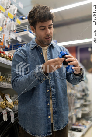 Man examining a pipe fitting for home renovation in a diy store Man examining a pipe fitting for home renovation in a diy store 138361312