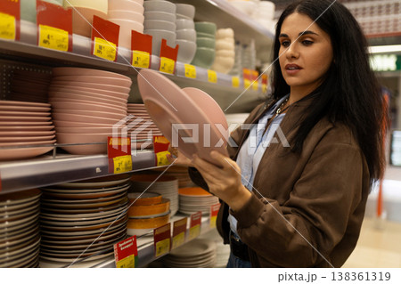 Woman choosing plates and bowls for home in a retail store Woman choosing plates and bowls for home in a retail store 138361319