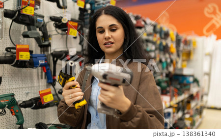Woman choosing between power drills in a hardware store Woman choosing between power drills in a hardware store 138361340