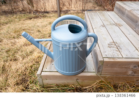Blue watering can on wooden garden steps outdoor spring gardening equipment close up Blue watering can on wooden garden steps outdoor spring gardening equipment close up 138361466