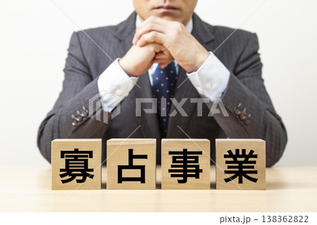「寡占事業」と書かれたブロックとビジネスマン 「寡占事業」と書かれたブロックとビジネスマン 138362822