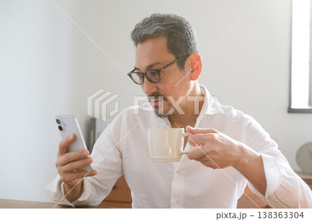 マグカップを持ちながらスマホを見る日本人男性 138363304