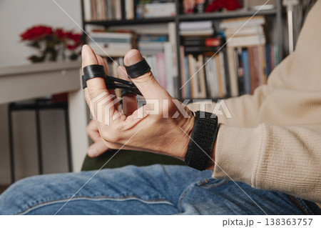 man stretches a finger resistance trainer at home 138363757