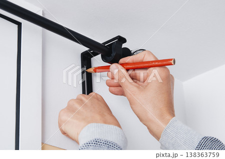 a man marks a drilling point on a wall 138363759
