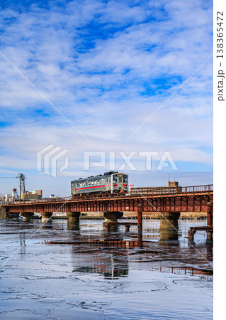 凍結した川を渡る列車と鉄橋 冬の北海道の鉄道風景 138365472