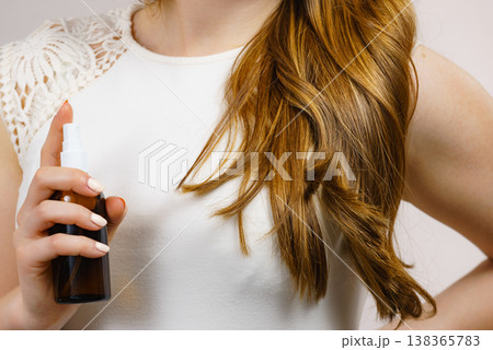 Woman applying hair cosmetic Woman applying hair cosmetic 138365783