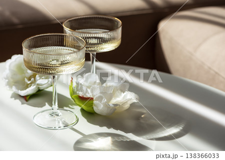 Champagne Glasses with Flowers under Sunlight. Elegant Celebration Scene 138366033