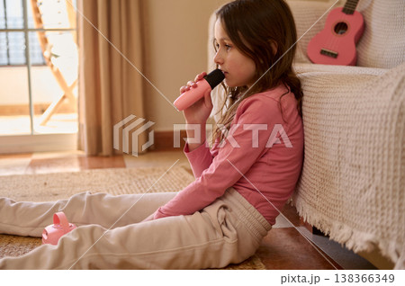 Young Girl Singing Into Toy Microphone While Sitting On Living Room Floor Young Girl Singing Into Toy Microphone While Sitting On Living Room Floor 138366349