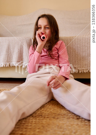 Young Girl Sitting On Floor With Pink Toy Kazoo Relaxing In Cozy Living Room 138366356