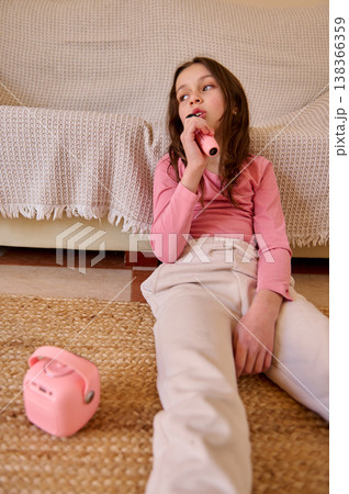 Young Girl Singing Into Microphone At Home On Living Room Floor With Pink Speaker 138366359