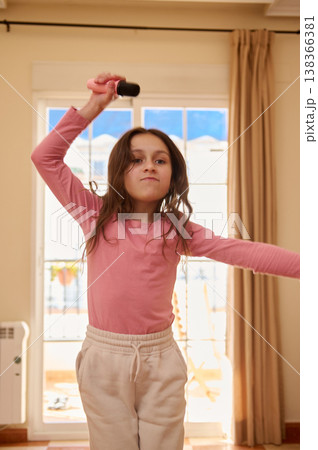 Young Girl Singing With Microphone In Living Room Having Fun And Expressive Play At Home 138366381