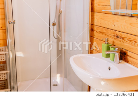 Wooden cabin bathroom with modern shower cabin, sink, and natural warm interior design 138366431