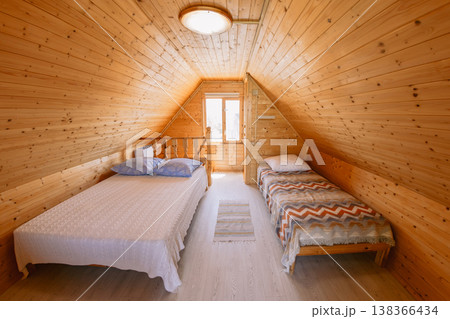 Bedroom with wooden walls, two beds, soft light, and warm rustic interior Bedroom with wooden walls, two beds, soft light, and warm rustic interior 138366434