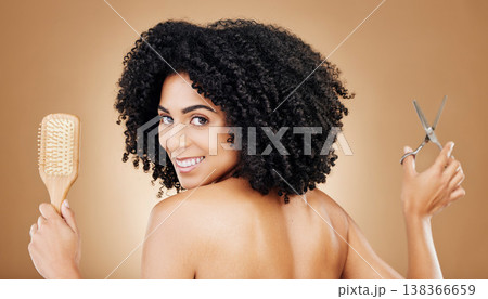 Hair care, portrait and a woman with a brush and scissors for grooming, styling or beauty. Smile, hairdresser and a young girl with an afro and tools for a hairstyle or cut on a studio background 138366659